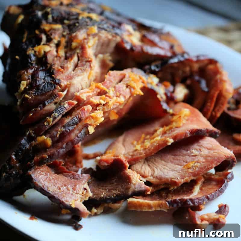 Orange Glazed ham with orange zest on a white plate