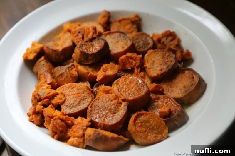 Golden Glazed Slow Cooker Sweet Potatoes 3 Overhead view of slow cooker candied sweet potatoes glistening with a sweet glaze in a rustic white serving dish, garnished with fresh herbs and a hint of rosemary.