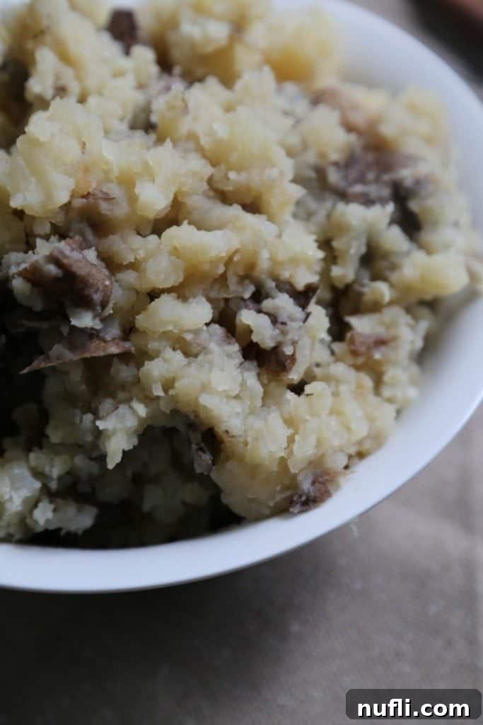 Crock Pot Garlic Mashed Potatoes in a white serving bowl, ready to be enjoyed, presented on a simple brown placemat.