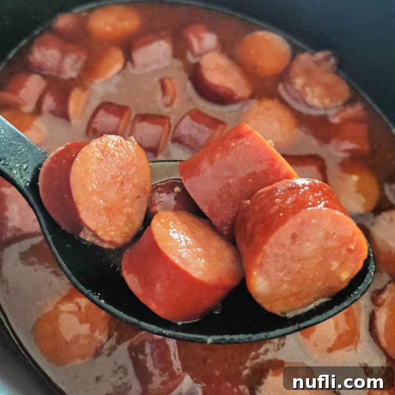 Easy Slow Cooker Appetizers 12 Crock Pot Barbecue Beer Kielbasa on a spoon, lifted from the slow cooker
