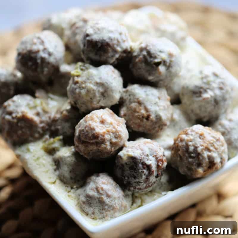 Easy Slow Cooker Appetizers 22 Swedish Meatballs stacked in a white square dish, covered in gravy