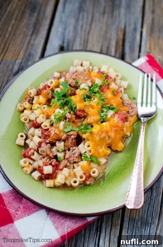 A close-up of a green plate featuring the delicious cheeseburger pasta casserole, with a fork poised to scoop up a cheesy, meaty bite.