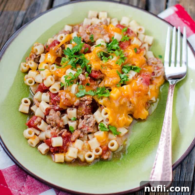 A generous serving of Cheeseburger Casserole on a green plate, with a fork ready to dig into this hearty and satisfying meal.