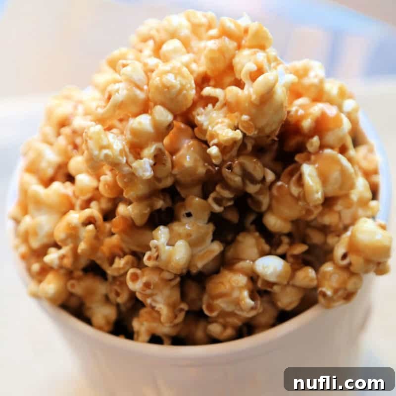 Salted Caramel Popcorn in a white popcorn tub with more popcorn in the background.