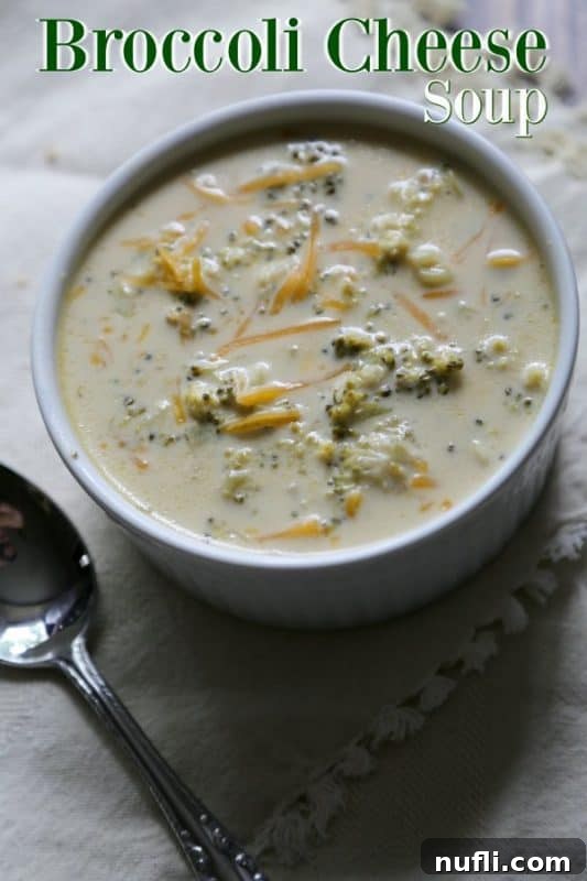 Broccoli Cheese Soup over a white bowl with soup and a silver spoon