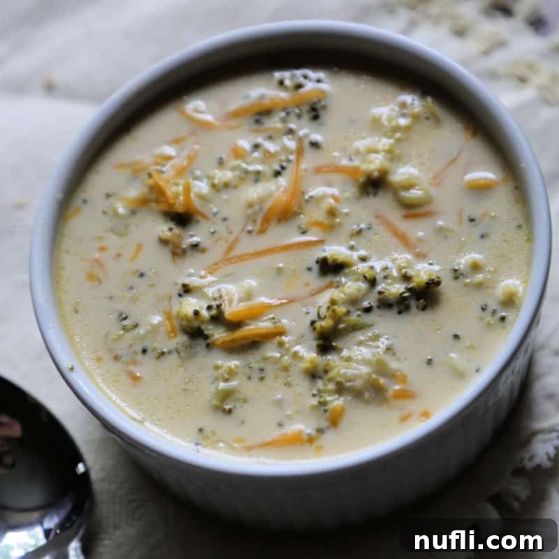 Crock Pot Broccoli Cheese Soup in a white bowl next to a spoon
