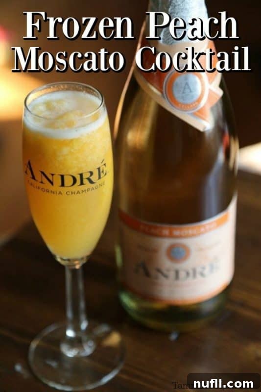 Frozen Peach Moscato Cocktail served in a champagne glass, with a bottle of Andre Peach Moscato in the background.