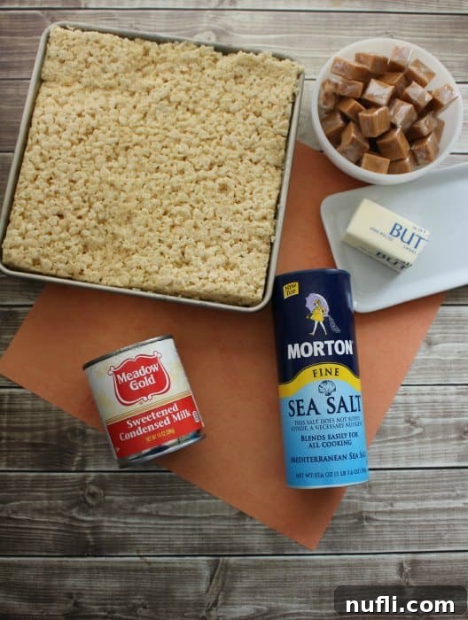Ingredients for Rice Krispie treats laid out on a table: Rice Krispie squares in a pan, sweetened condensed milk, sea salt, and caramels, ready for preparation.