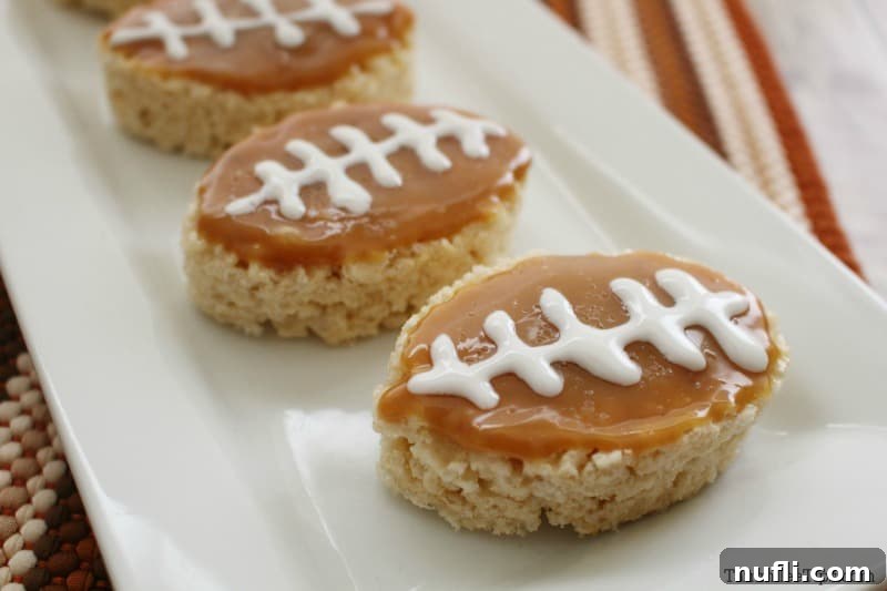 Rice Krispie footballs with caramel topping and white icing laces beautifully arranged on a white platter.