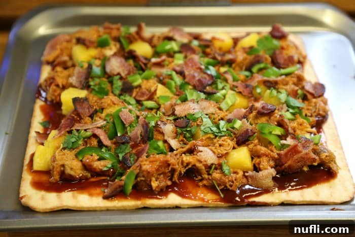 pulled pork pizza ready to bake on a baking sheet