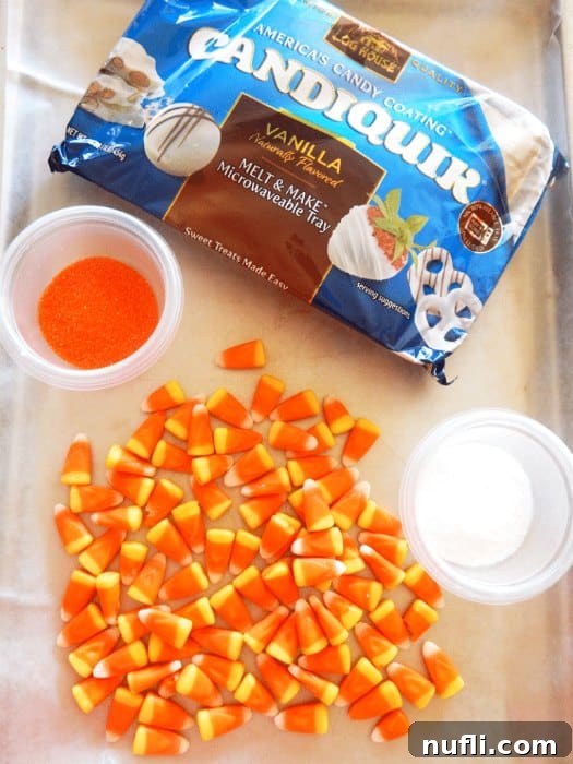 Ingredients for Candy Corn Bark including white almond bark, candy corn, and orange sprinkles on a baking tray.