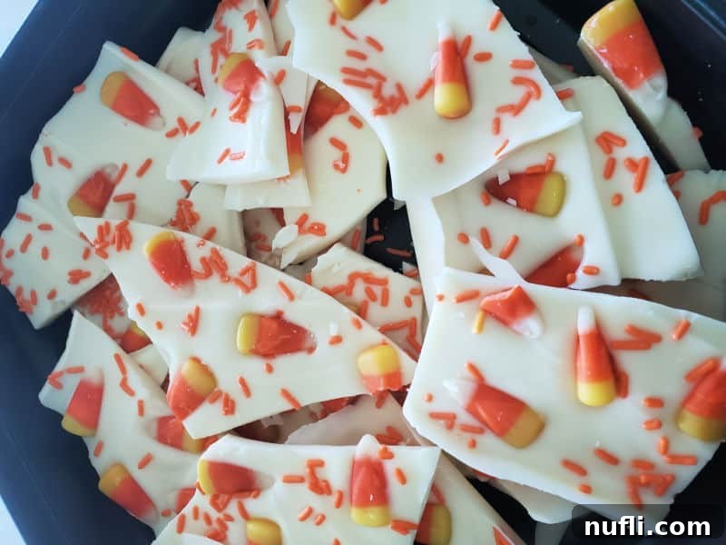 Assorted pieces of Candy Corn Bark in a dark bowl, showcasing the festive colors and textures.