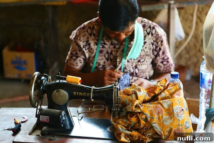 Skilled artisan operating a traditional Singer sewing machine, adding finishing touches to batik fabric products in Bali