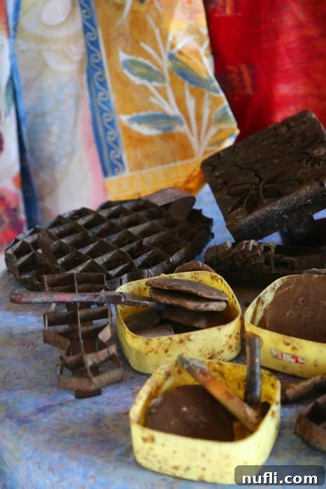 Assortment of traditional batik tools, including cantings and wax pots, laid out on a wooden table