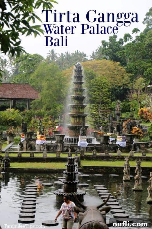 Bali's Tirta Gangga: Royal Water Gardens 2 Tirta Gangga Water Palace Bali, featuring a traditional Balinese temple structure surrounded by water and ancient statues, under a clear sky.