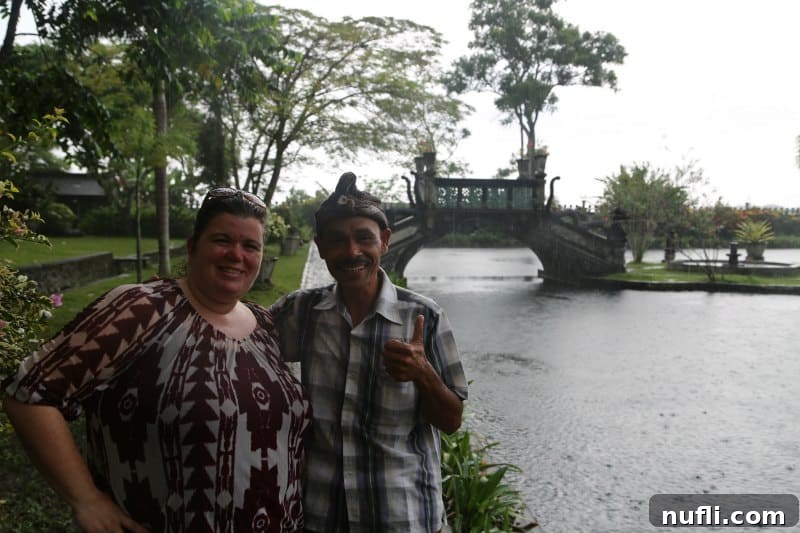 Bali's Tirta Gangga: Royal Water Gardens 4 A couple, Tammilee and their Bali guide, standing by the water with a traditional bridge in the background at Tirta Gangga.