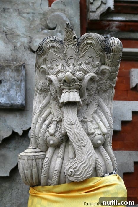A unique stone carving of a figure with its tongue out, adorned with traditional offerings, within the grounds of Ulun Danu Beratan Temple