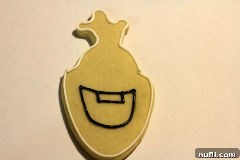 Partially decorated Olaf cookie showing piped black mouth outline and white edge.