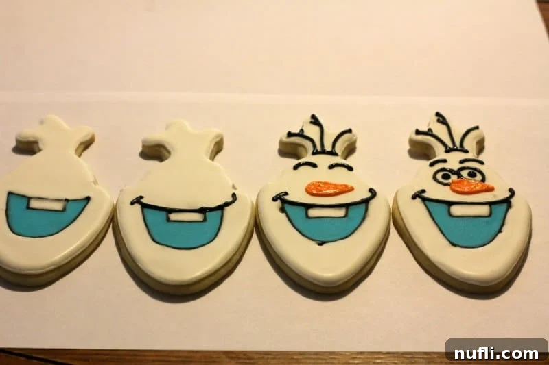 Several Olaf cookies in various stages of decoration on a white surface.