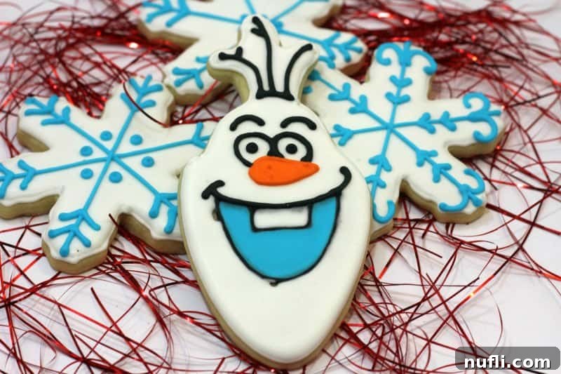 Completed Olaf cookie placed beside a beautifully decorated blue and white snowflake cookie.