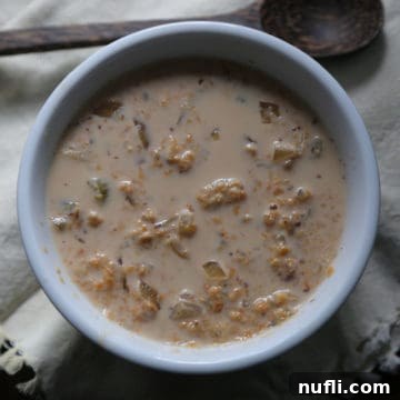 Sweet Potato Stew in a white bowl with a wooden spoon, ready to be served.