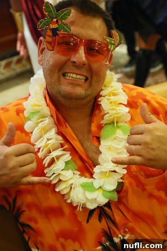 A man joyfully dressed in a vibrant Hawaiian shirt, a floral lei, and fun, oversized sunglasses, embodying the spirit of a 'tacky tourist' on a Carnival Halloween Cruise.