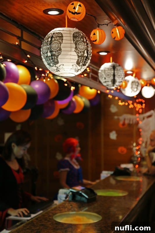 Festive Halloween decorations, including cobwebs and spooky ornaments, adorn the Guest Services area, adding to the ship's eerie charm for the Carnival Halloween Cruise.