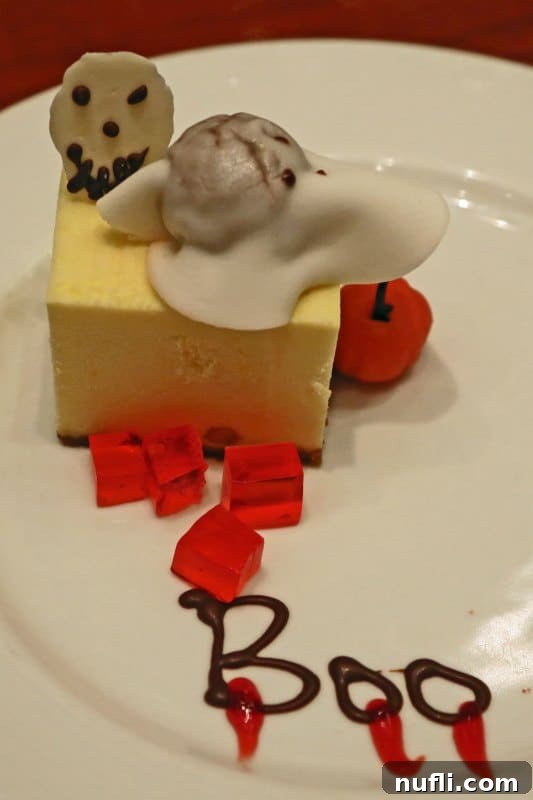 A decadent 'Boo' Halloween-themed dessert, likely a cheesecake, elegantly presented on a plate, showcasing the culinary creativity on a Carnival Cruise.