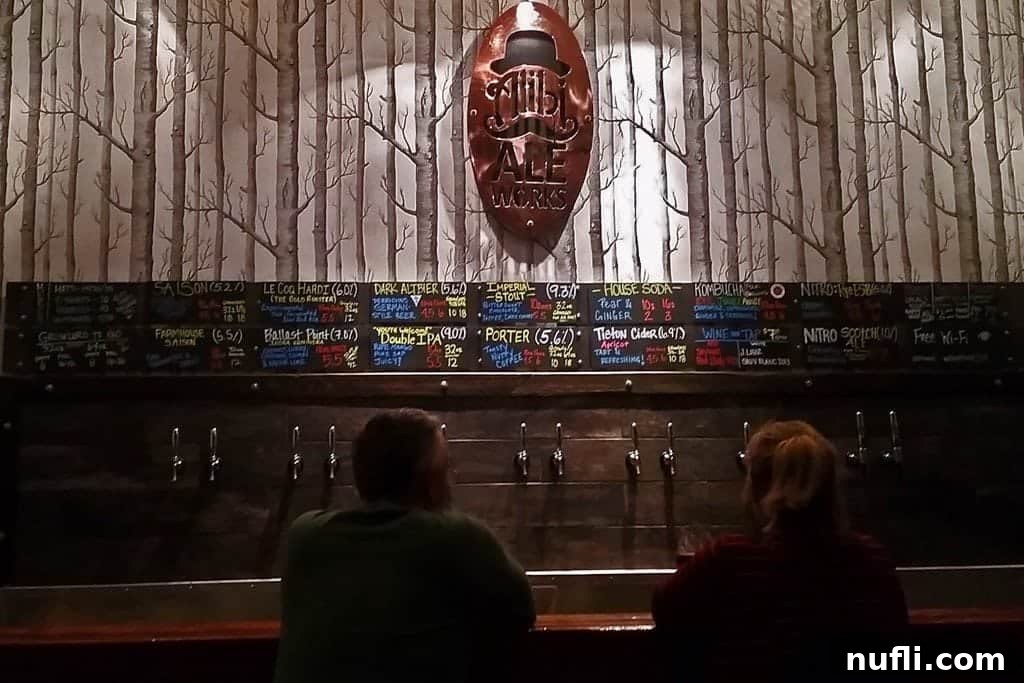 Alibi Ale Works sign above a bustling bar counter, showcasing a vibrant brewery atmosphere
