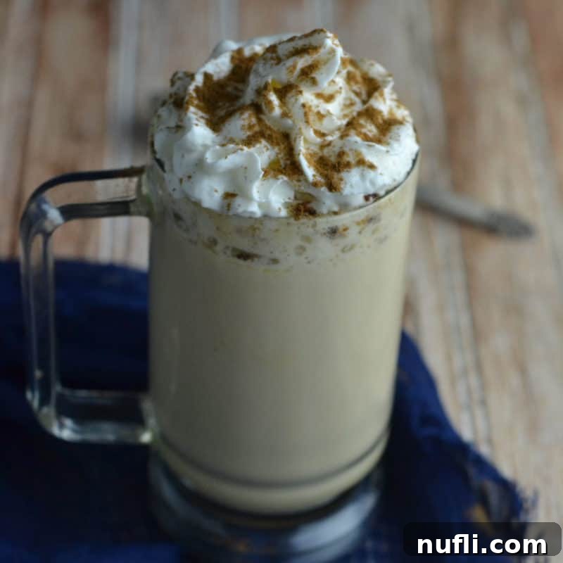 Close-up of a festive Eggnog Latte in a glass mug topped generously with whipped cream and a sprinkle of cinnamon, perfect for a cozy winter day.