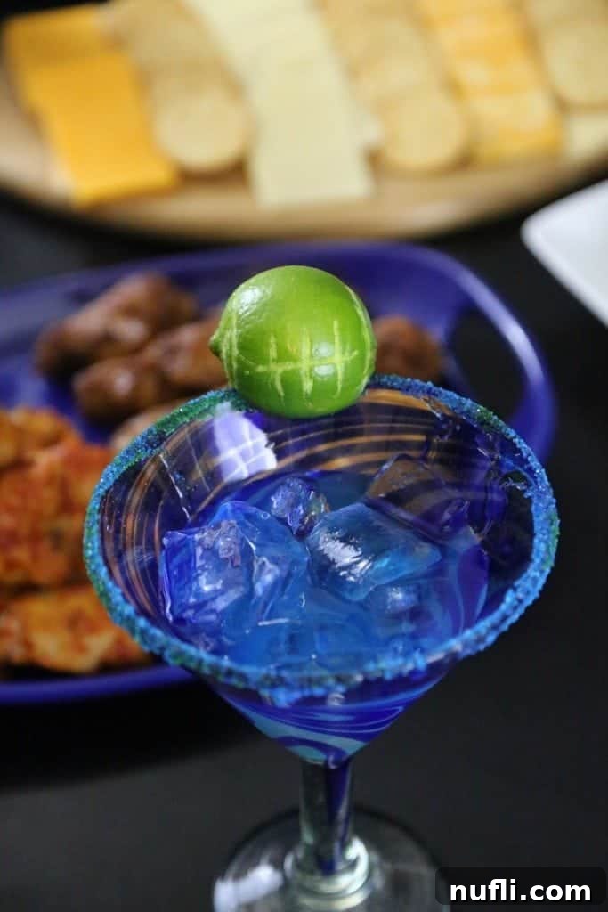 Close-up of the Hawk-Arita cocktail being poured into a margarita glass, showcasing its vibrant blue color