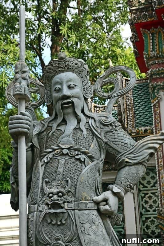 Close-up of a guardian statue adorned with a staff and a distinctive dragon belt buckle, typical of Wat Pho's intricate and diverse decor.