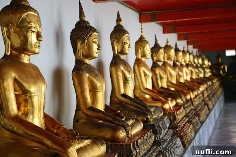 A serene row of smaller golden Buddha statues in a beautifully adorned temple hall within the Wat Pho complex, showcasing the temple's rich collection.
