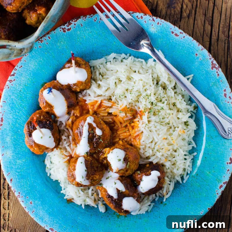 Spicy Buffalo Chicken Meatballs served alongside fluffy white rice on a blue plate, with a fork ready to enjoy this flavorful dish.