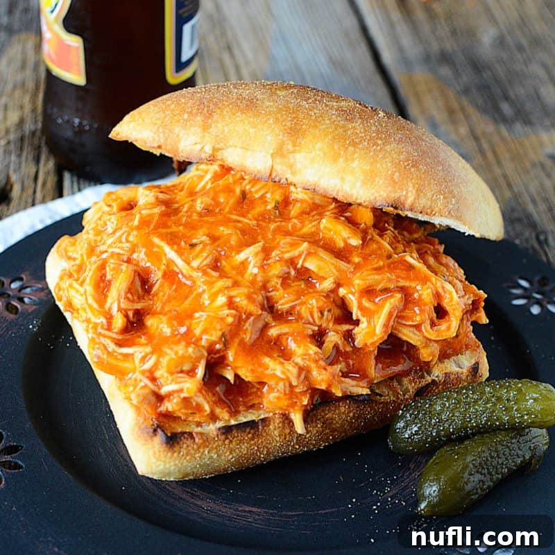 A delicious Buffalo Ranch Chicken sandwich, featuring tender pulled chicken on a bun, accompanied by two crisp pickle slices.
