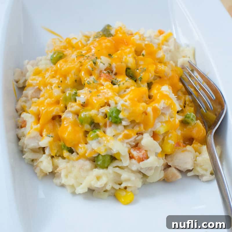 A serving of creamy Chicken Orzo Casserole, presented on a white plate with a fork, ready for a comforting and satisfying meal.
