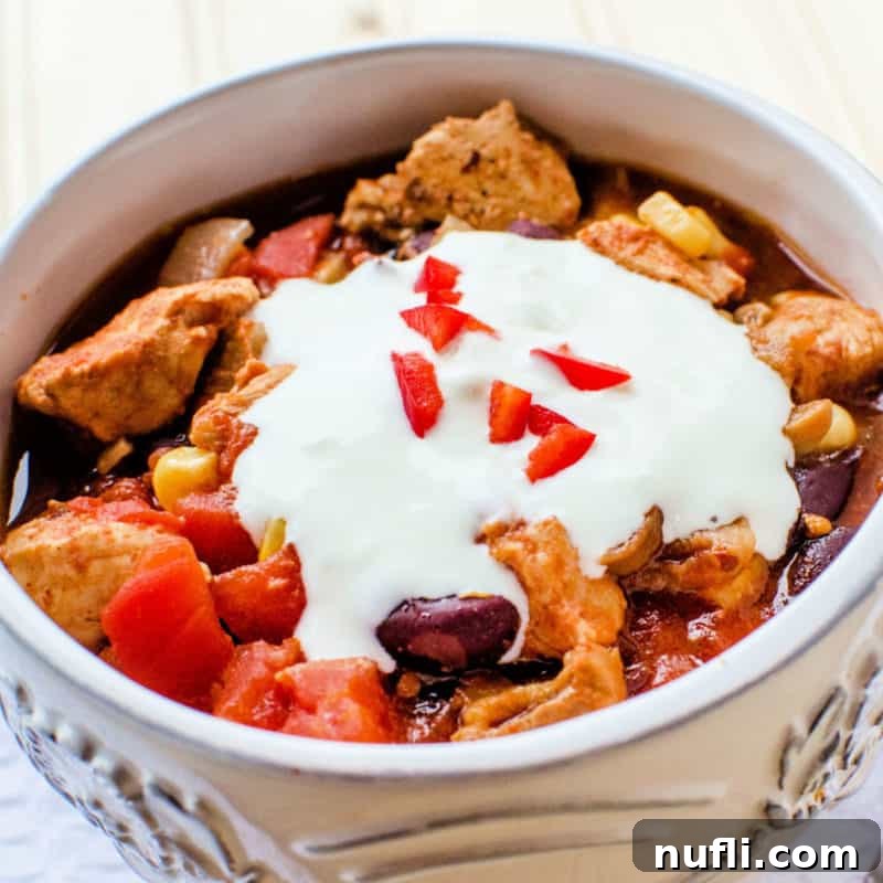 A warm, inviting bowl of Southwest Crockpot Chicken Chili, garnished with a swirl of sour cream, promising a flavorful and hearty meal.