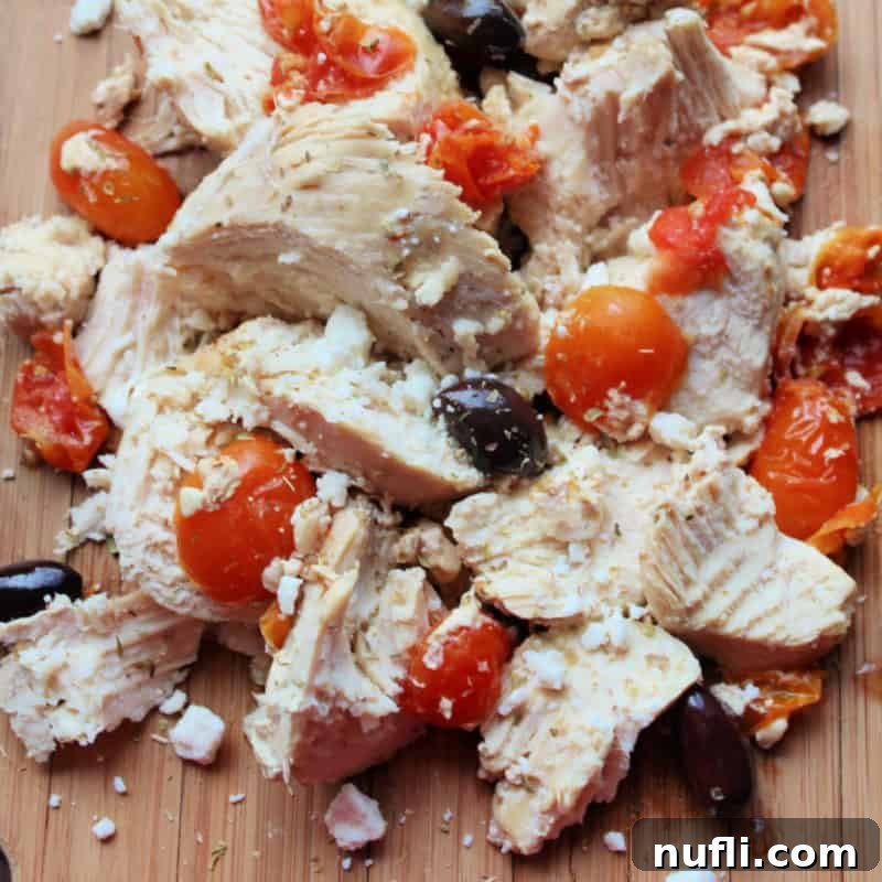 Flavorful Greek chicken, adorned with fresh tomatoes and briny Kalamata olives, presented invitingly on a plate.
