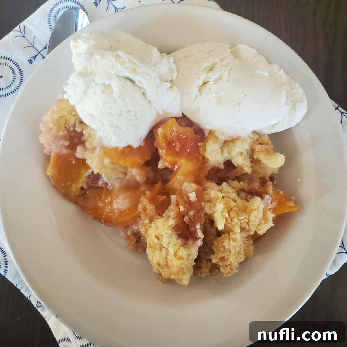 Over 40 Simple Plant-Based Slow Cooker Meals 17 Crock Pot Peach Cobbler with vanilla ice cream in a white bowl, a warm and fruity dessert