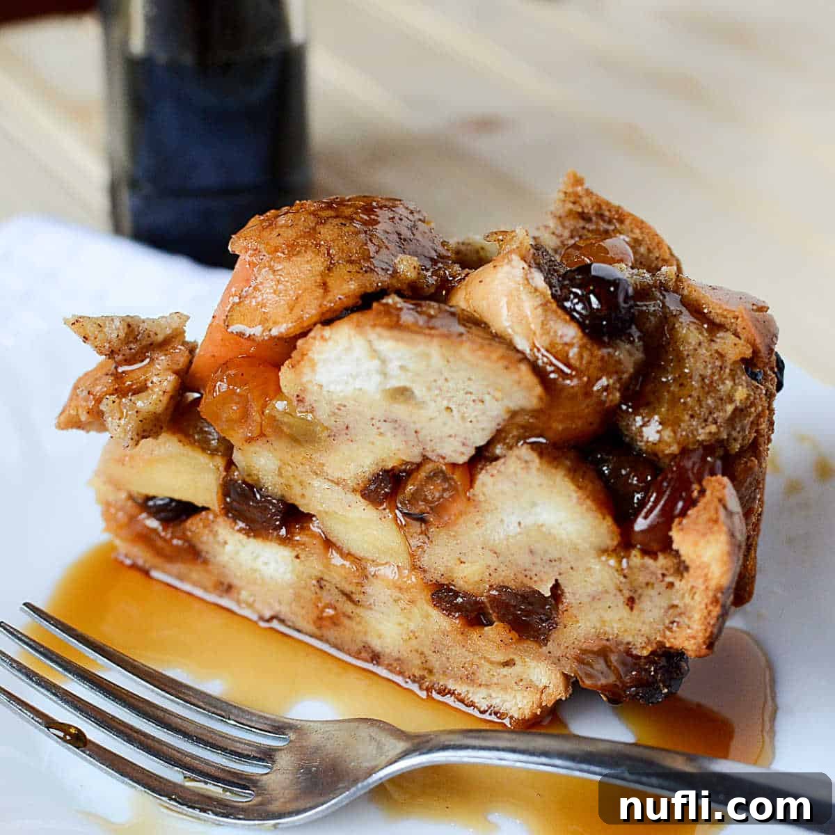 Over 40 Simple Plant-Based Slow Cooker Meals 20 Apple Raisin French Toast on a white plate with syrup and a silver spoon, a comforting breakfast