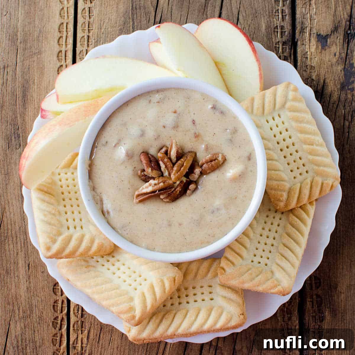Over 40 Simple Plant-Based Slow Cooker Meals 22 Praline Dip in a white bowl surrounded by cookies and apple slices, a sweet slow cooker dessert