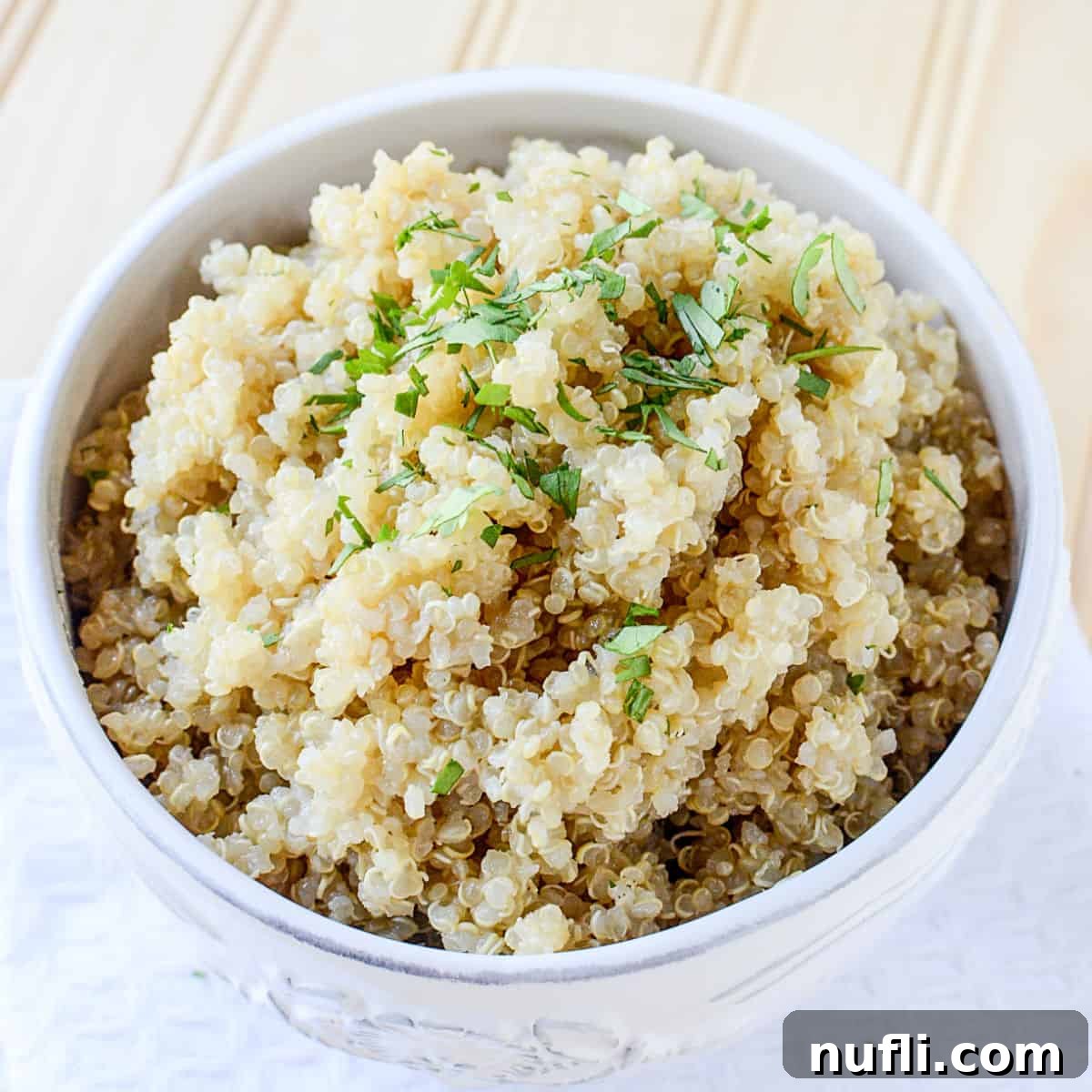 Over 40 Simple Plant-Based Slow Cooker Meals 40 Cooked Quinoa in a white bowl on a white napkin, a healthy and versatile grain