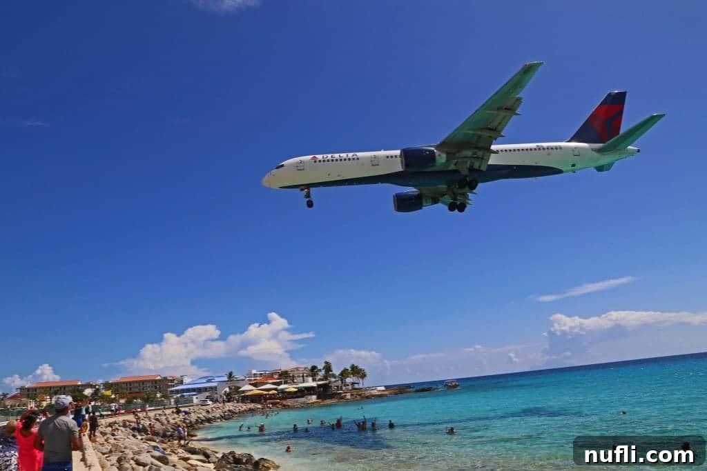 Plane flying over Maho Beach with people in the water
