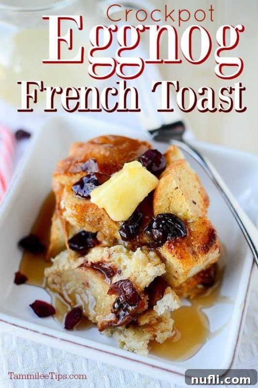 Crockpot Eggnog French toast on a white plate with a silver spoon, garnished with cranberries and powdered sugar.