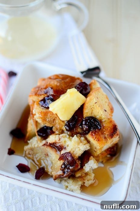 Close-up of Crockpot Eggnog French toast on a white plate with a fork, ready to be enjoyed.