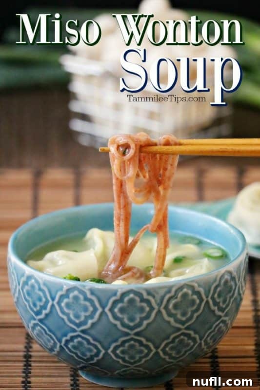 Miso wonton soup over a blue bowl with chopsticks holding noodles