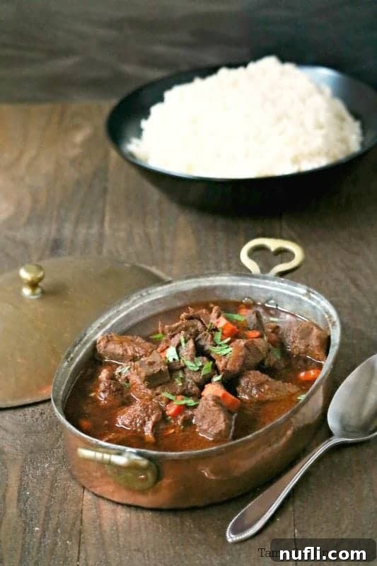 goulash in a metal pot near a bowl of rice