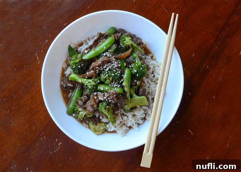 Slow Cooker Beef and Broccoli 3 Slow cooker beef and broccoli over white rice in a white bowl with chopsticks