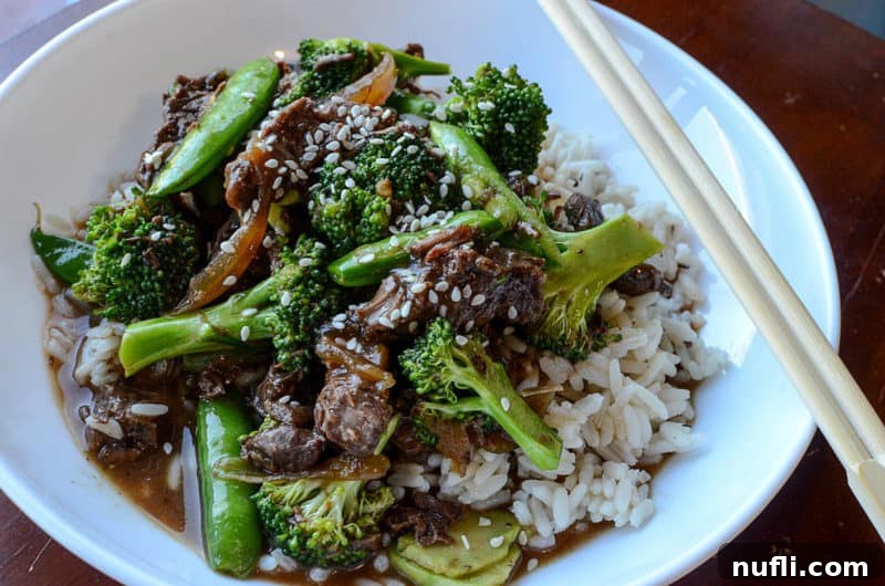 Slow Cooker Beef and Broccoli 4 beef and broccoli over rice in a white bowl with chopsticks