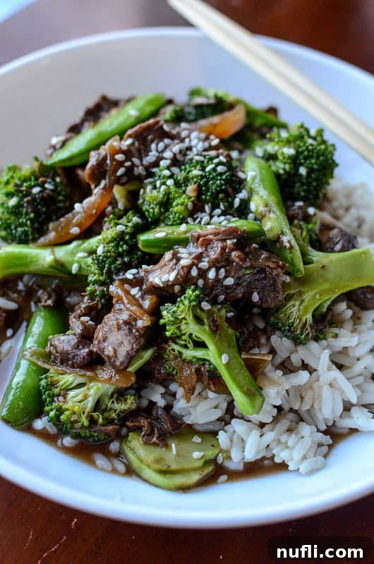 Slow Cooker Beef and Broccoli 5 Beef and broccoli over white rice in a bowl with chopsticks